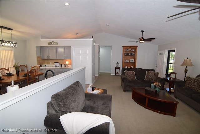 living room with ceiling fan, light colored carpet, and vaulted ceiling