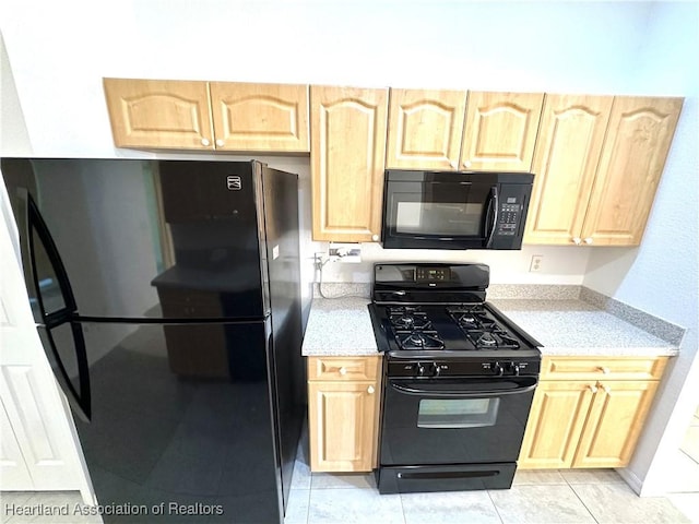 kitchen featuring light tile patterned floors, light brown cabinets, and black appliances