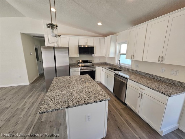 2859 N Lancaster Rd, Avon Park, FL 33825 - kitchen featuring wood finished floors, stainless steel appliances, vaulted ceiling, a sink, and a textured ceiling