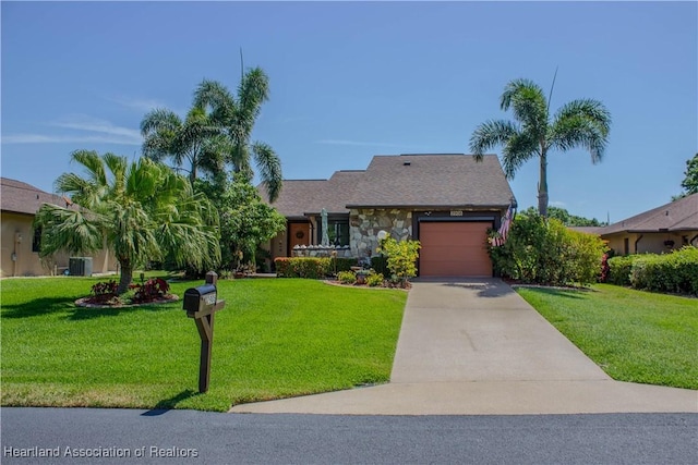 ranch-style house featuring a front yard, driveway, an attached garage, and central air condition unit