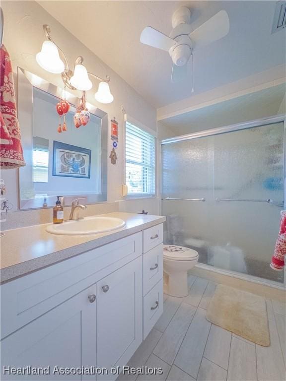 full bath featuring a shower stall, vanity, toilet, a ceiling fan, and visible vents