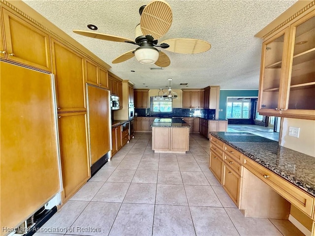 kitchen featuring a textured ceiling, light tile patterned floors, a wealth of natural light, and stainless steel appliances