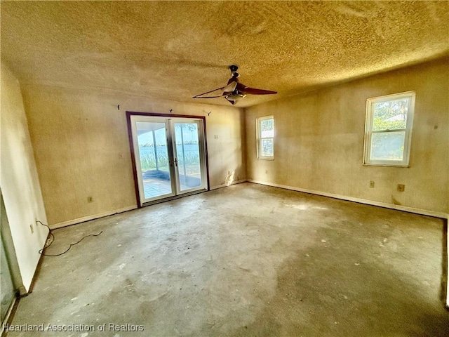 empty room featuring ceiling fan, a textured ceiling, french doors, baseboards, and unfinished concrete floors