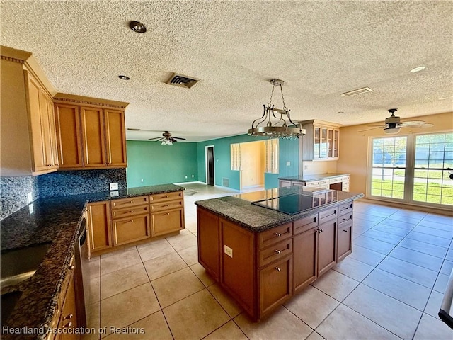 kitchen featuring ceiling fan, brown cabinetry, a kitchen island, and black electric cooktop