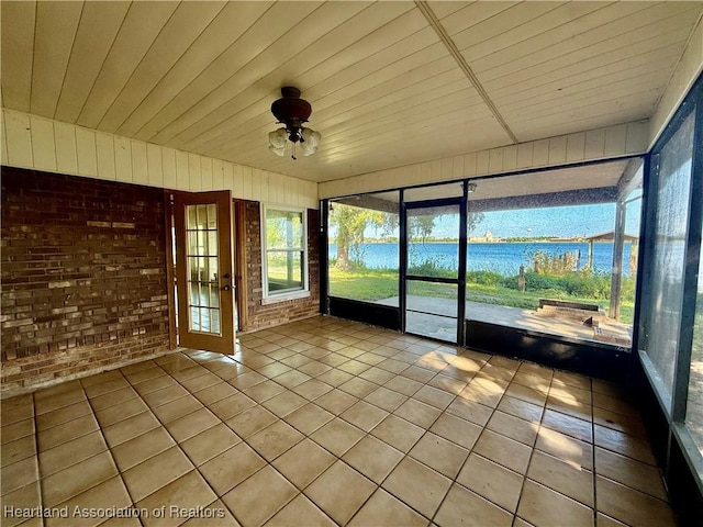 unfurnished sunroom featuring a water view and a ceiling fan