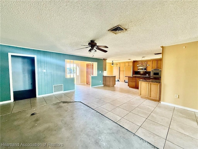 unfurnished living room featuring visible vents, a ceiling fan, baseboards, and a textured ceiling
