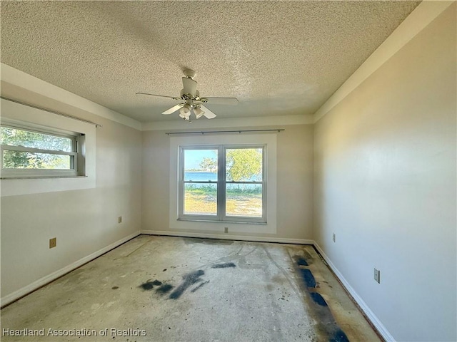 spare room featuring baseboards, a ceiling fan, and a textured ceiling