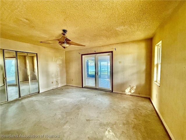 unfurnished room featuring french doors, a textured ceiling, baseboards, and unfinished concrete floors