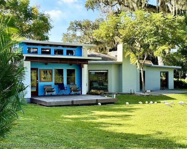 rear view of property featuring a lawn and a wooden deck