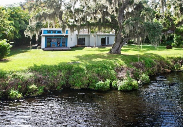 back of house featuring a water view and a lawn