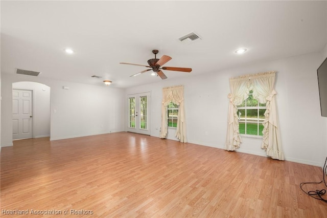 empty room featuring arched walkways, healthy amount of natural light, ceiling fan, light wood-type flooring, and recessed lighting