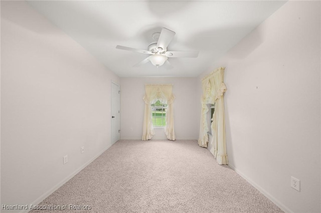 carpeted empty room featuring a ceiling fan and baseboards