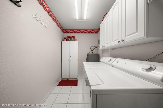 clothes washing area with cabinet space, washer and clothes dryer, light tile patterned floors, and baseboards