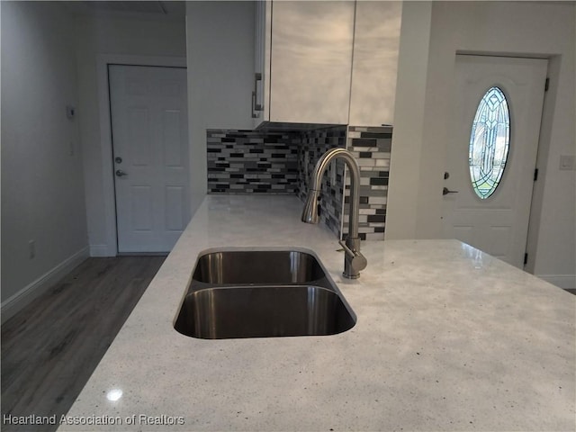 kitchen with backsplash, light stone counters, and sink