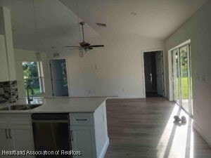 kitchen featuring dishwashing machine, sink, white cabinetry, plenty of natural light, and lofted ceiling