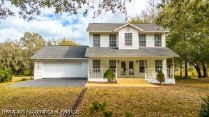 11200 S Jefferson Ave, Lake Placid, FL 33852 - traditional home with an attached garage, covered porch, and driveway