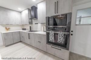 11200 S Jefferson Ave, Lake Placid, FL 33852 - kitchen with wall chimney exhaust hood, modern cabinets, gray cabinets, oven, and built in microwave