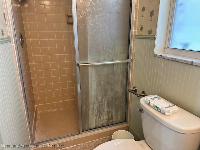 bathroom featuring wainscoting, a shower stall, and toilet