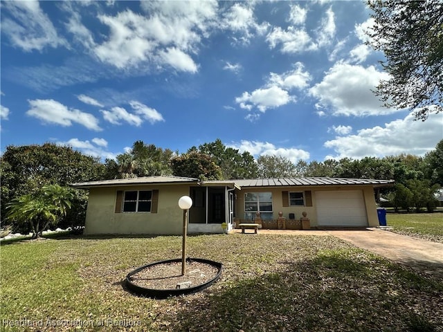 ranch-style home with driveway, metal roof, an attached garage, a standing seam roof, and a front lawn