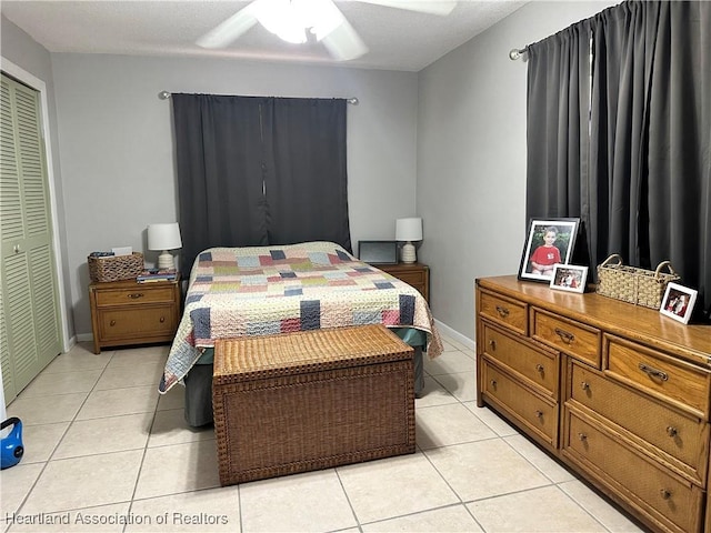 bedroom featuring ceiling fan, a closet, light tile patterned flooring, and baseboards