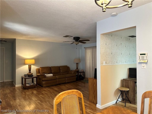 living room with a ceiling fan, a textured ceiling, baseboards, and wood finished floors