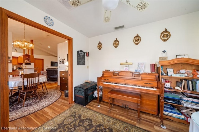 miscellaneous room with lofted ceiling, hardwood / wood-style floors, and a notable chandelier