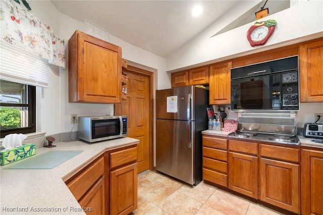 kitchen featuring lofted ceiling, light tile patterned floors, sink, and appliances with stainless steel finishes