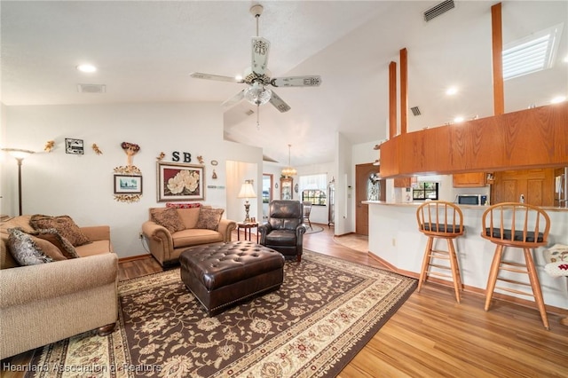 living room with ceiling fan, high vaulted ceiling, and light wood-type flooring