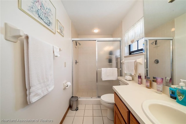 bathroom featuring tile patterned floors, vanity, toilet, and a shower with shower door