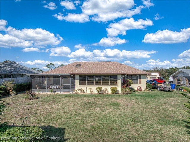 rear view of house featuring a sunroom and a lawn