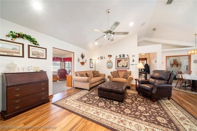 living room with ceiling fan with notable chandelier, lofted ceiling, and light hardwood / wood-style floors