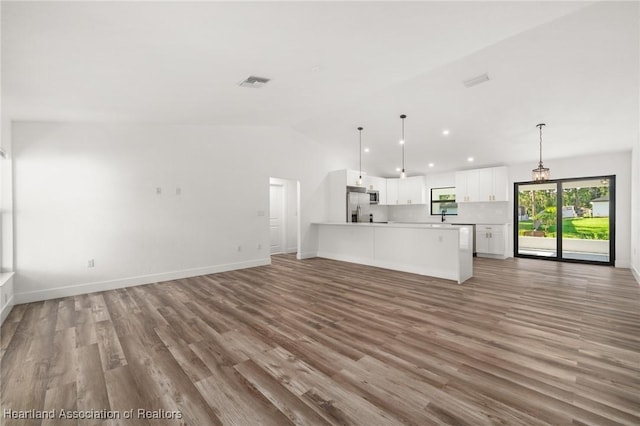 111 Blue Moon Ave, Lake Placid, FL 33852 - unfurnished living room featuring light wood-type flooring, recessed lighting, baseboards, a sink, and lofted ceiling