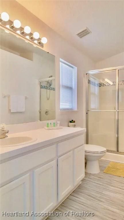 bathroom with a shower with door, vanity, and toilet