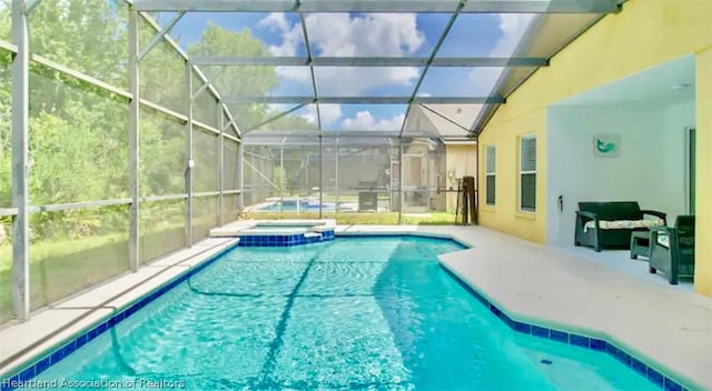 view of swimming pool with glass enclosure, a patio area, and an in ground hot tub