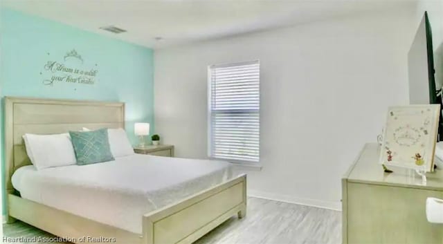 bedroom with light hardwood / wood-style floors and multiple windows