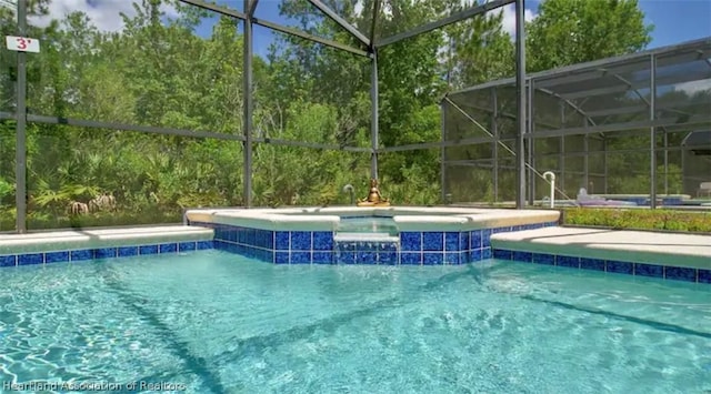 view of swimming pool with glass enclosure and an in ground hot tub