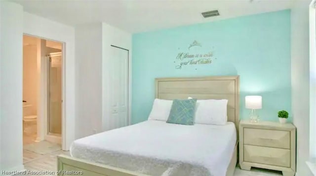 bedroom with ensuite bath and light tile patterned flooring