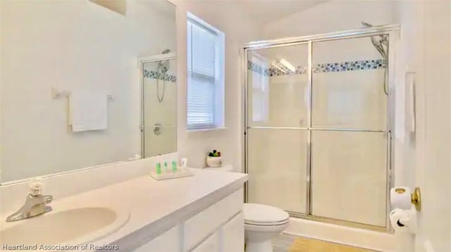 bathroom with vanity, toilet, and a shower with door