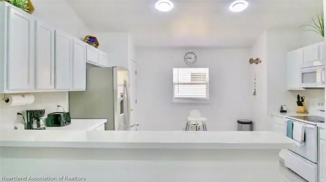 kitchen with white cabinets, white appliances, and kitchen peninsula