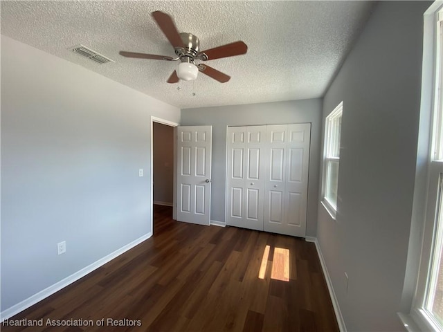 unfurnished bedroom featuring a textured ceiling, dark hardwood / wood-style flooring, a closet, and ceiling fan