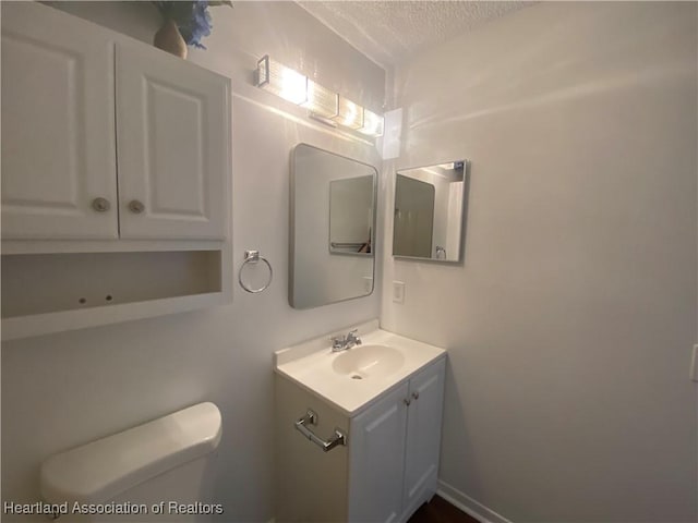 bathroom featuring a textured ceiling, vanity, and toilet