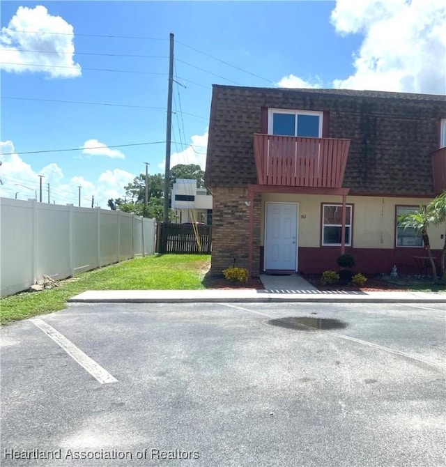 view of front of property featuring a balcony and a front lawn