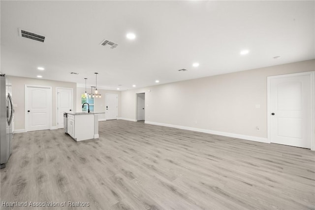 unfurnished living room featuring recessed lighting, visible vents, a sink, light wood-type flooring, and baseboards