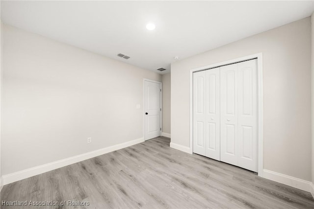 unfurnished bedroom with wood finished floors, baseboards, and a closet