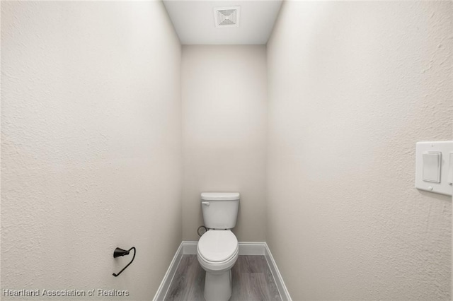 bathroom with wood finished floors, visible vents, toilet, and baseboards
