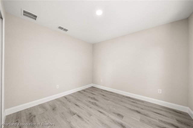 empty room featuring baseboards, wood finished floors, and visible vents