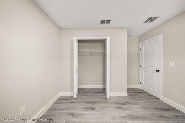 unfurnished bedroom with baseboards, a closet, visible vents, and light wood-style flooring