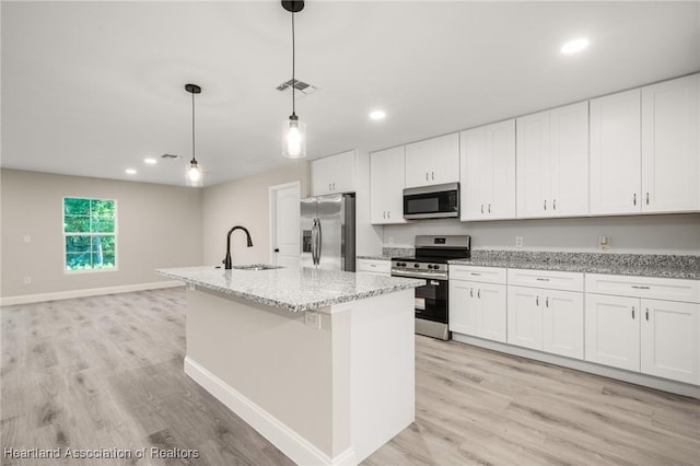 kitchen with light wood finished floors, stainless steel appliances, a kitchen island with sink, a sink, and recessed lighting