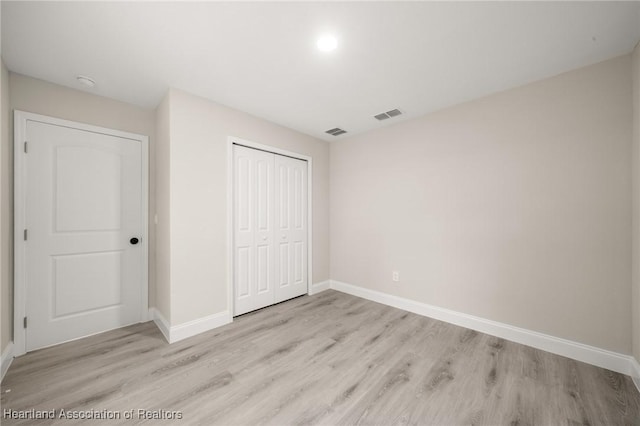 unfurnished bedroom with a closet, light wood-style floors, visible vents, and baseboards