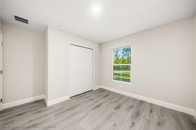 unfurnished bedroom with baseboards, a closet, visible vents, and light wood-style flooring